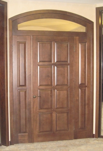 Дверной блок входной двустворчатый, массив сосны, с арочной остекленной фрамугой. Покрытие - морилка и лак. 